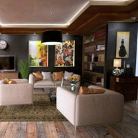 Salon contemporain avec bibliothèque intégrée, fauteuils beiges, œuvres d'art colorées et éclairage chaleureux