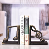 Serre-livre en résine représentant une croche et une clé de sol tenant des livres sur une table.