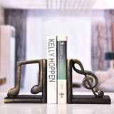 Serre-livre en résine représentant une croche et une clé de sol tenant des livres sur une table.