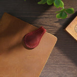 Marque-pages aimantés en cuir véritable cousu main de différentes couleurs disposés sur une table en bois