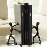 Serre-livre en métal noir représentant deux silhouettes poussant des livres sur une table

