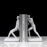 Serre-livre en résine blanche représentant deux silhouettes musclées tenant des livres entre elles.