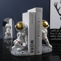 Serre-livre en résine représentant un astronaute sur un sol lunaire tenant des livres

